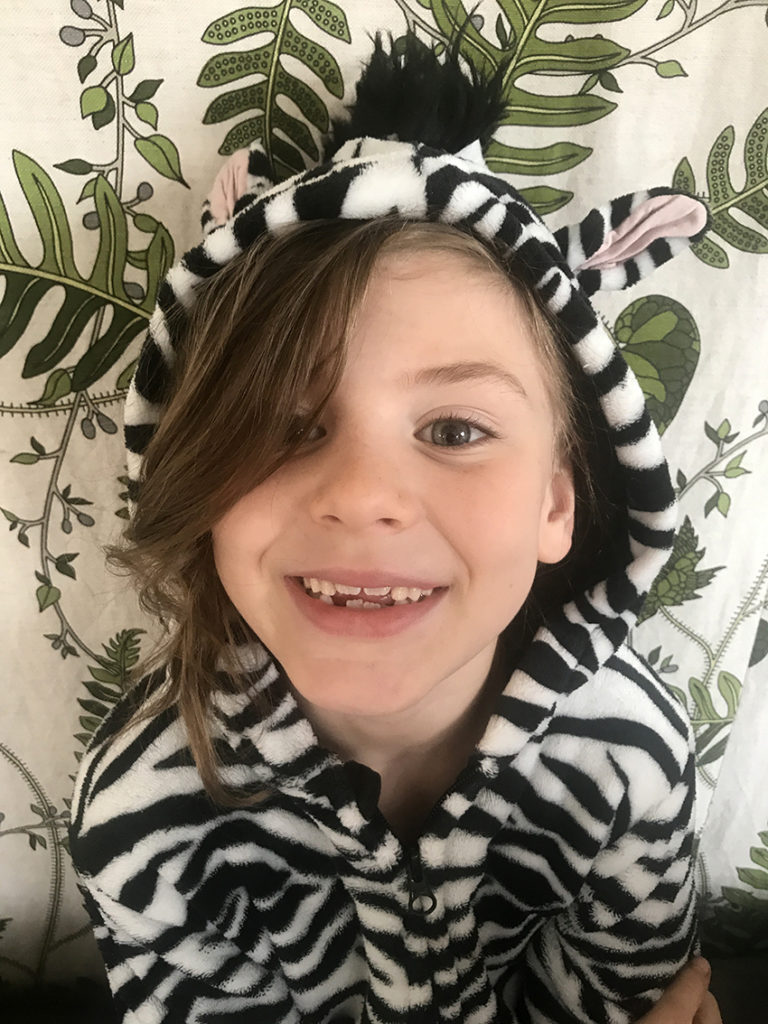 sexårig flicka i zebrarandig jacka med huva